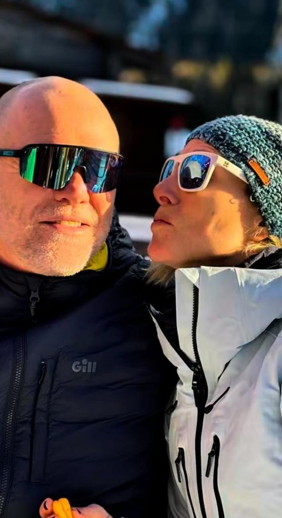 Zara leaning towards mike's cheek to kiss in ski wear