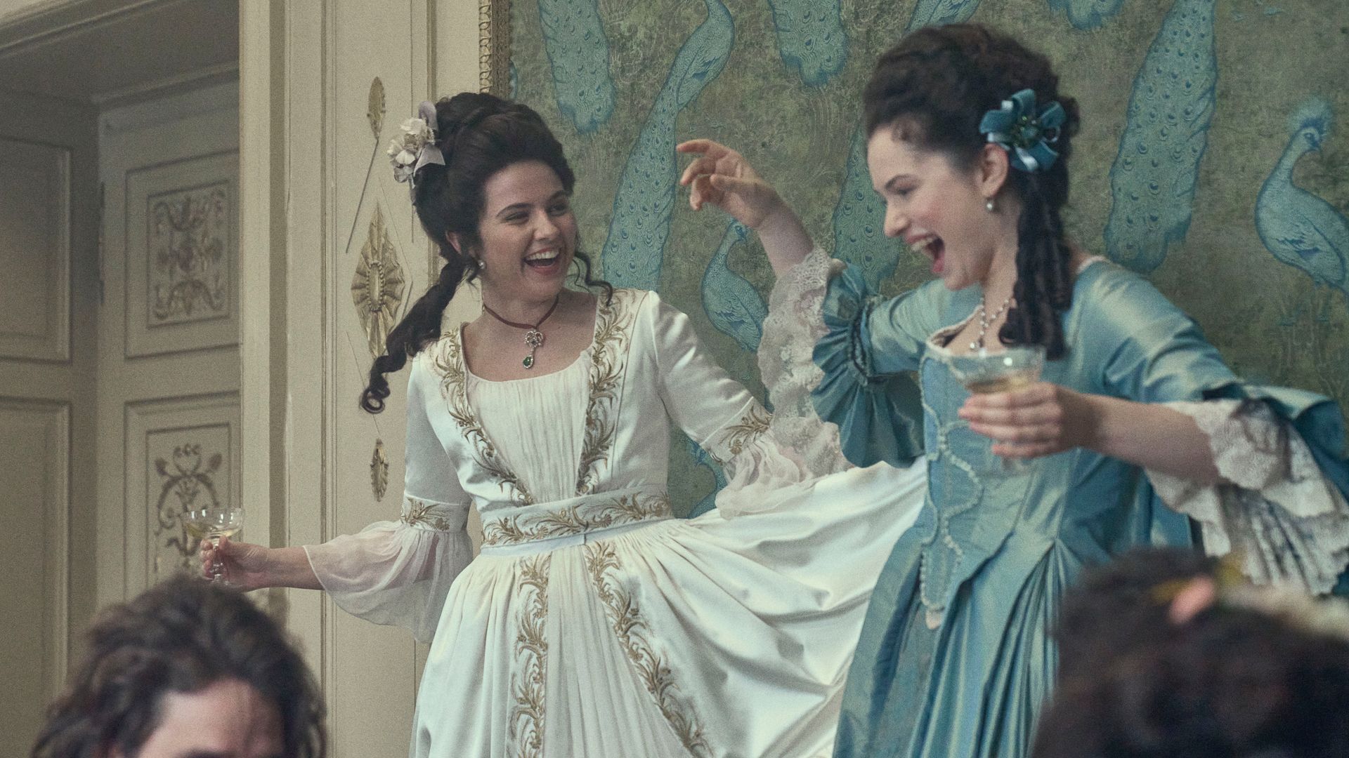 two women in 18th century clothing laughing and dancing