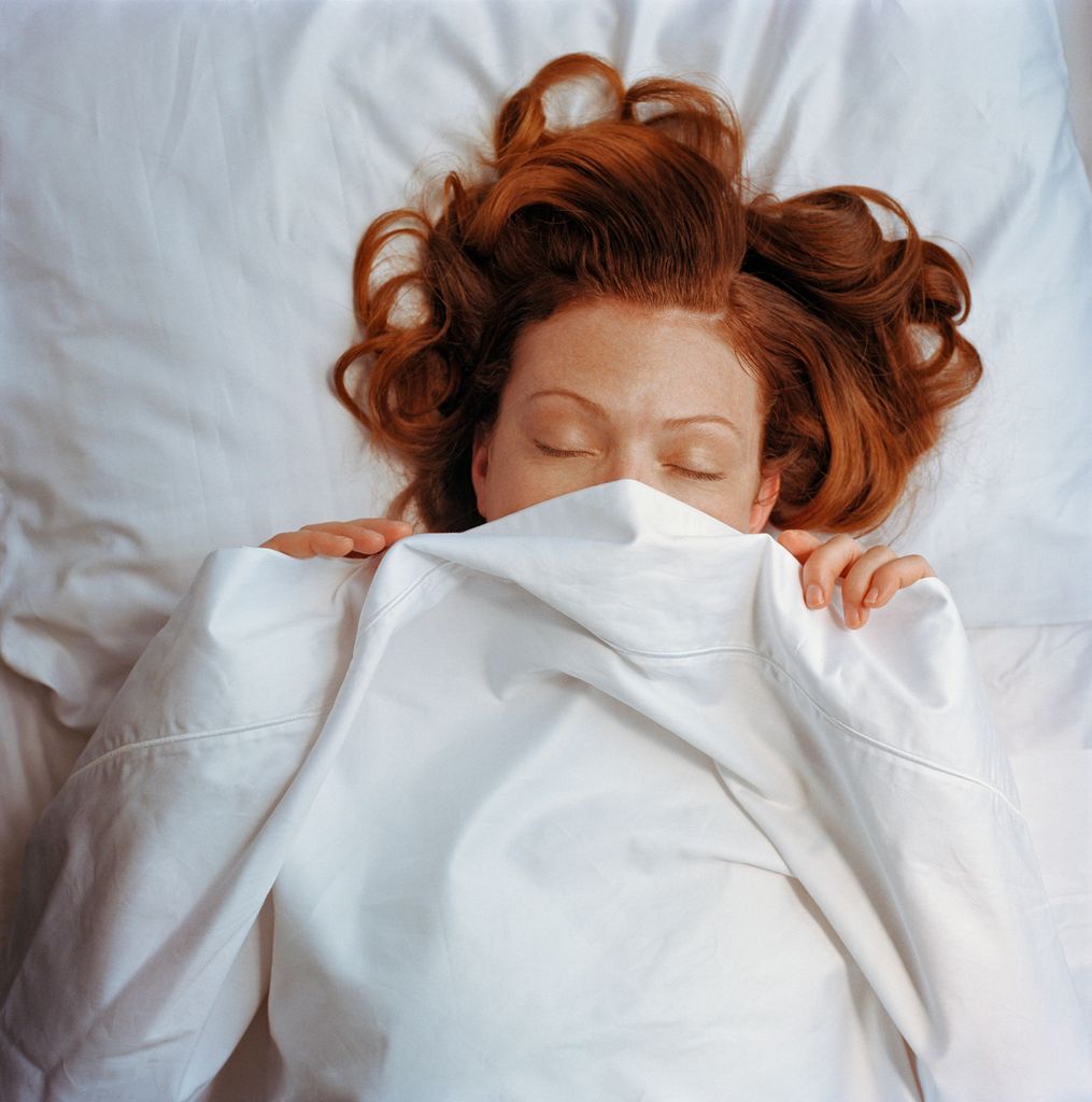 woman asleep with covers pulled over her face